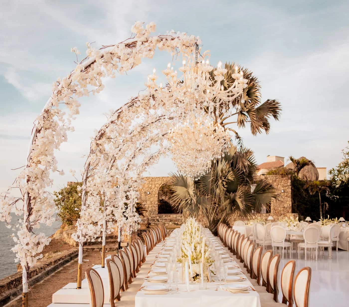 Mesa larga de boda junto al mar en Cartagena con arreglos florales y velas.